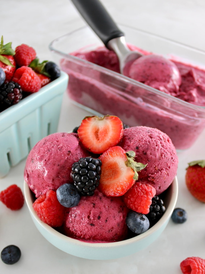 Mixed Berry Frozen Yogurt in blue bowl with fresh berries on top and in back