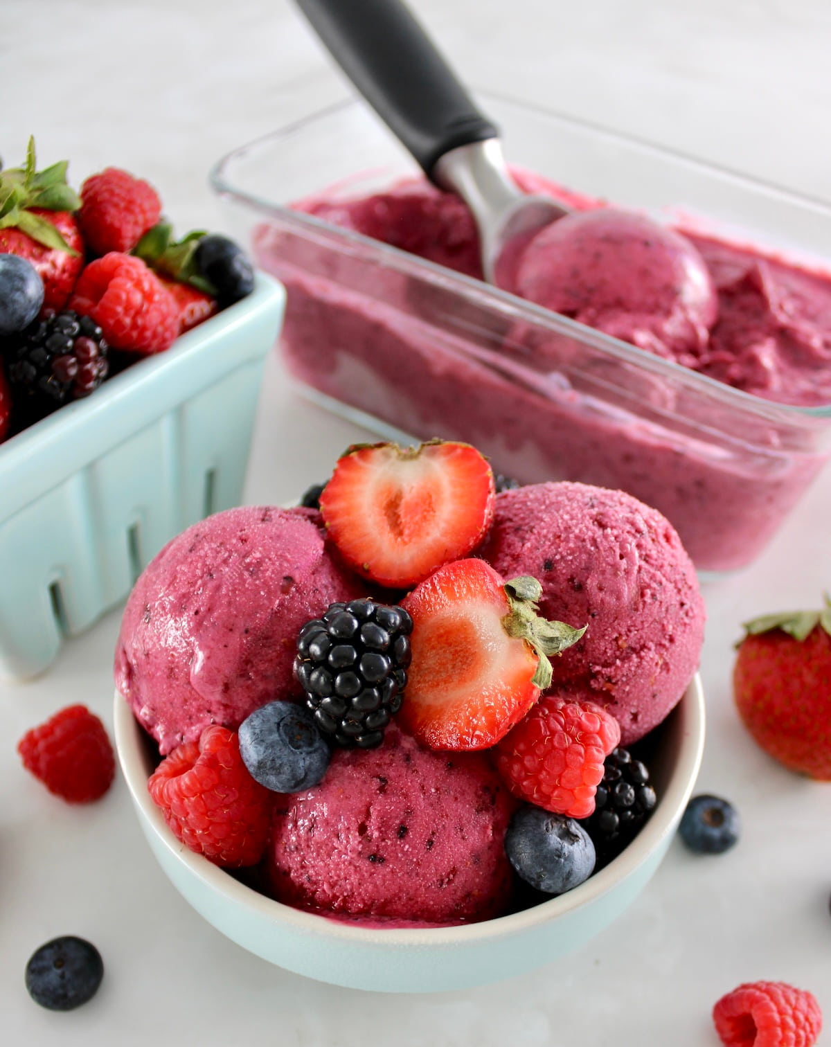 Mixed Berry Frozen Yogurt in blue bowl with fresh berries on top and in back