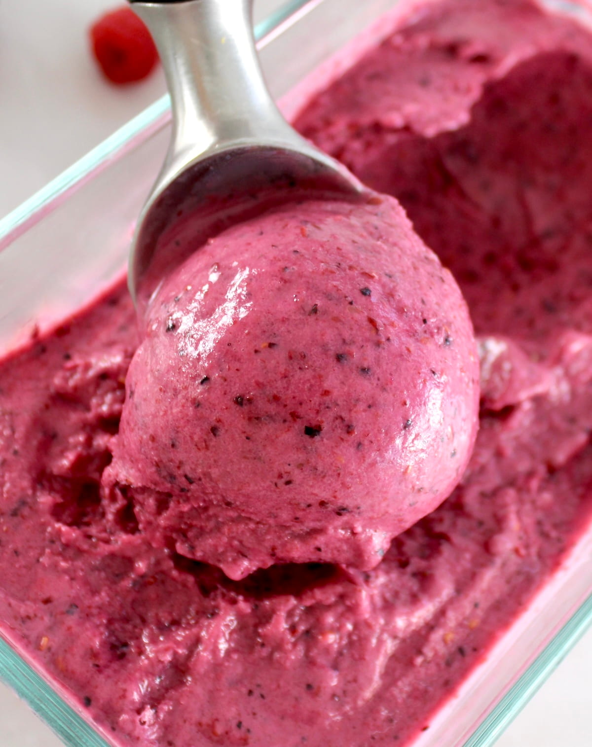 scooping Mixed Berry Frozen Yogurt with ice cream scooper in glass container