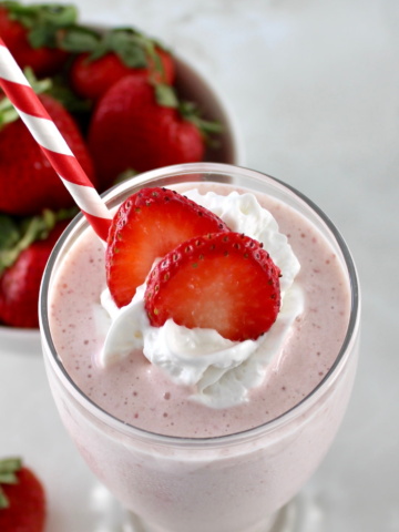 overhead closeup of Strawberry Protein Shake with strawberry slices and whip cream on top