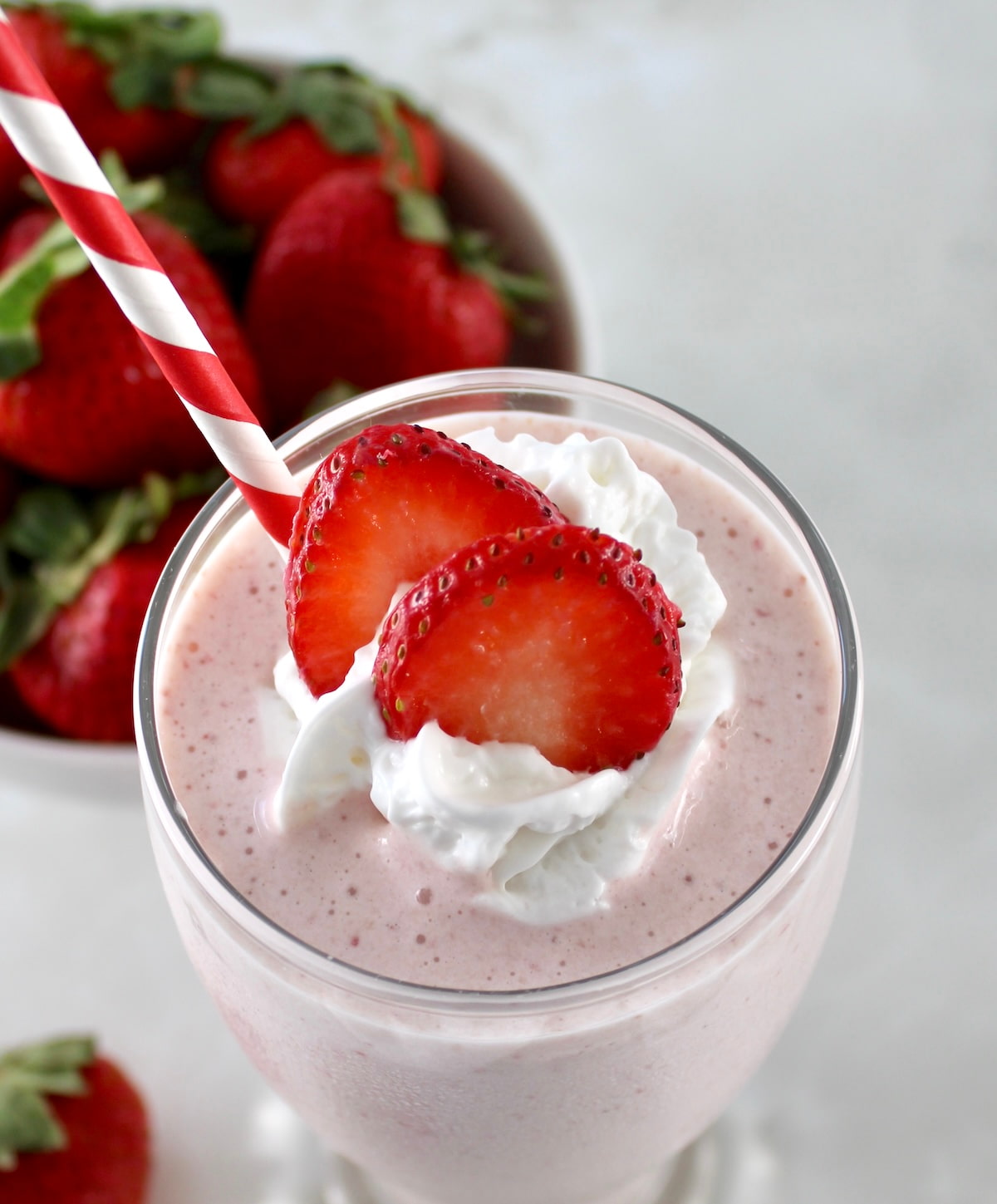 overhead closeup of Strawberry Protein Shake with strawberry slices and whip cream on top