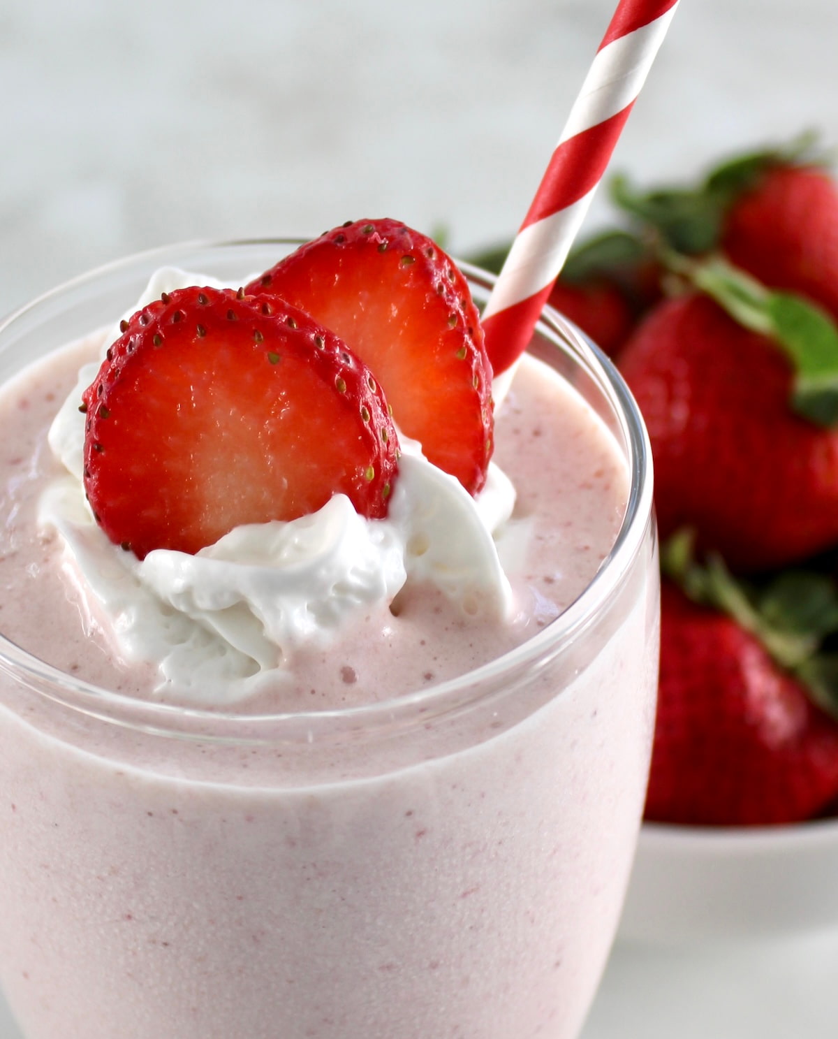 closeup side view of Strawberry Protein Shake in glass with strawberry slices and whip cream on top