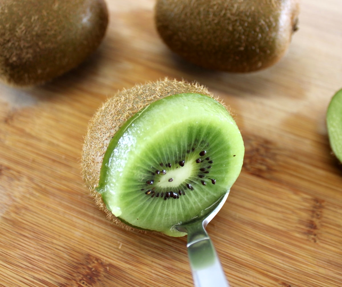 spoon carving out kiwi from the skin