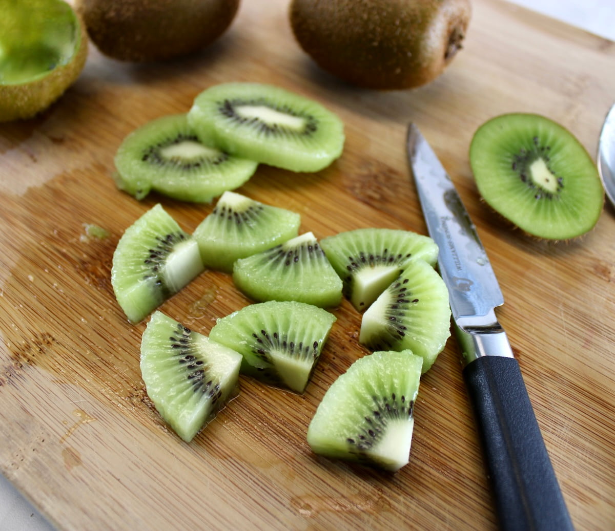 cut up kiwi on cutting board with pairing knife