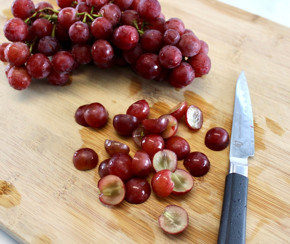 sliced red grapes on cutting board with paring knife