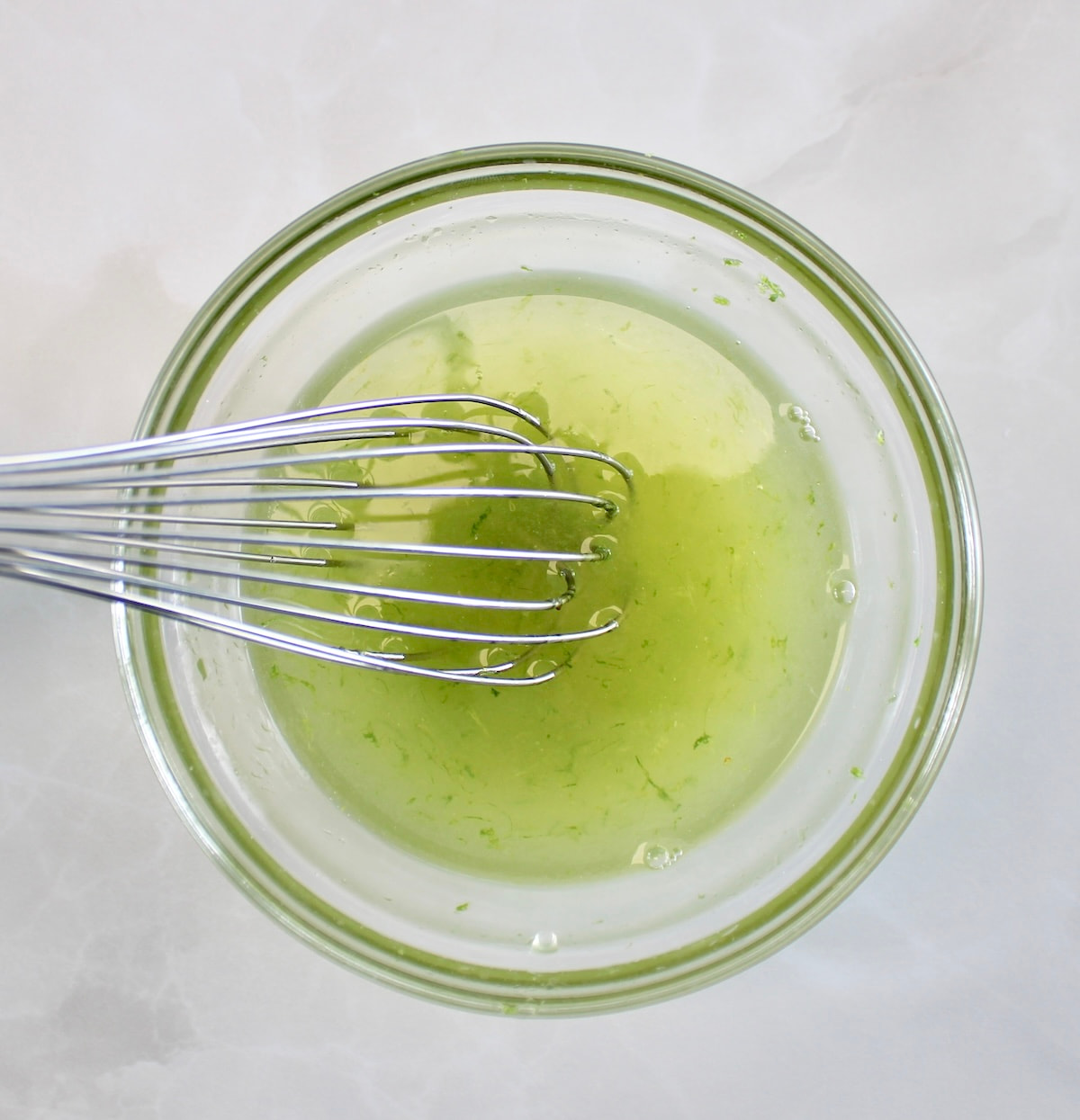 honey lime dressing in glass bowl with whisk
