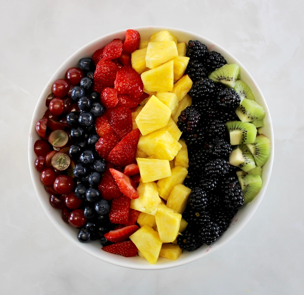 Easy Fruit Salad in white bowl arranged in vertical rows