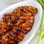 Grilled Asian Chicken on white plate with chopped scallions