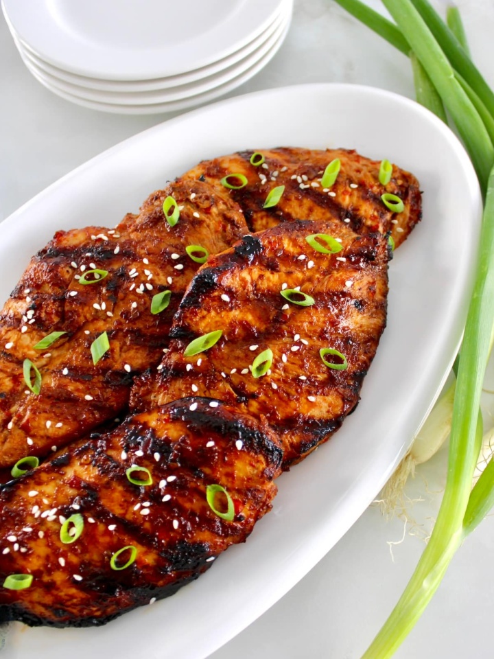 Grilled Asian Chicken on white plate with chopped scallions