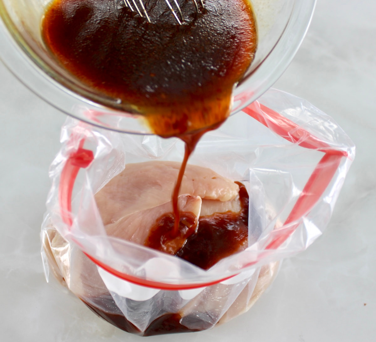 pouring asian marinade over chicken in food storage bag
