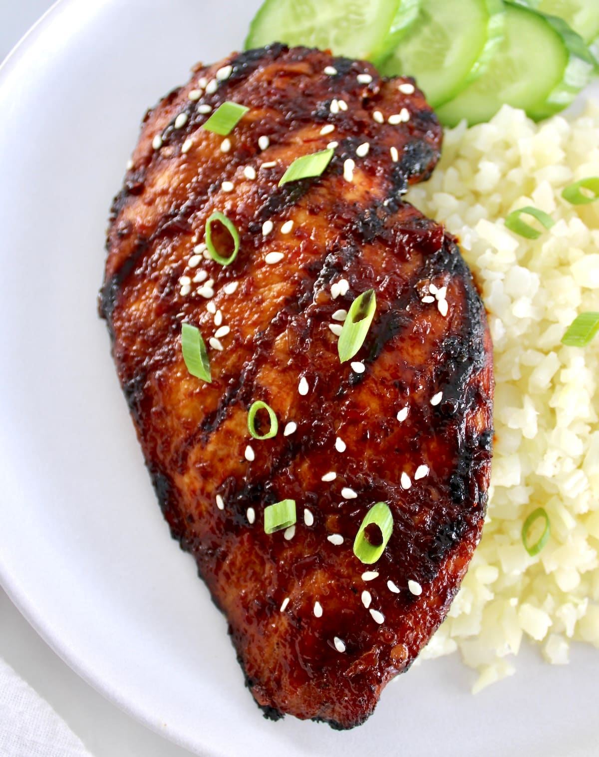 closeup overhead of Grilled Asian Chicken with cauliflower rice and cucumber on side