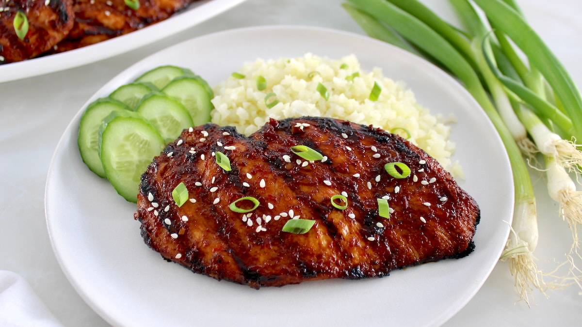 Grilled Asian Chicken on white plate with cauliflower rice and cucumber salads