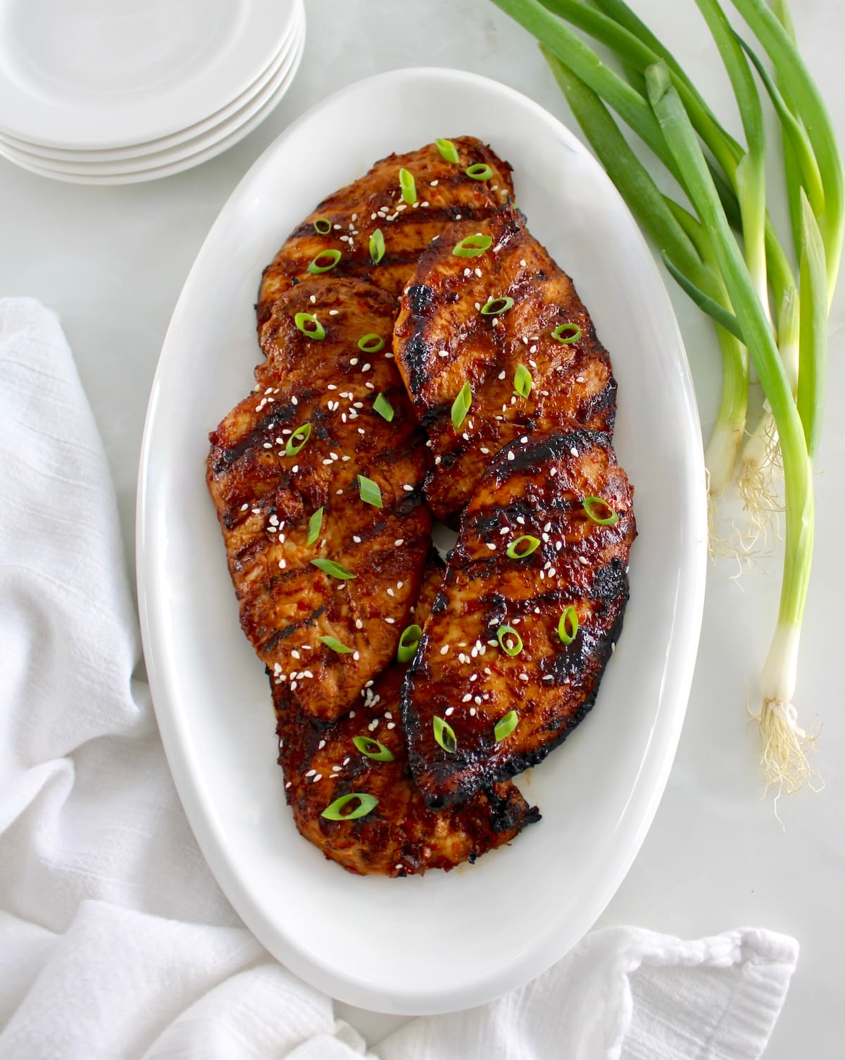 overhead view of Grilled Asian Chicken on white oval platter with chopped scallions