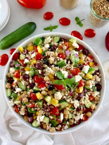 overhead view of Mediterranean Farro Salad in white bowl with fresh veggies around