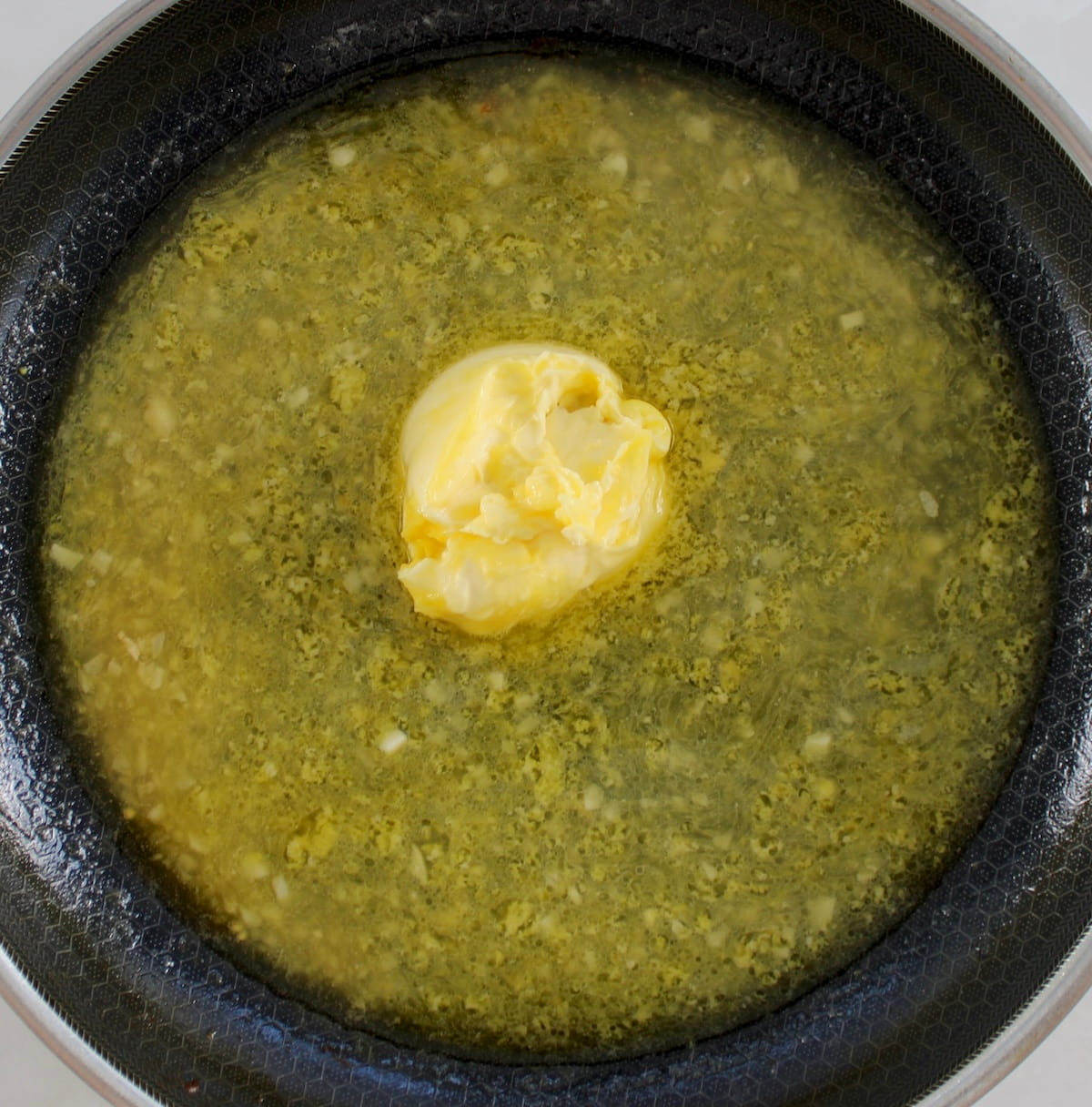Shrimp Scampi sauce with clump of unmelted butter in skillet