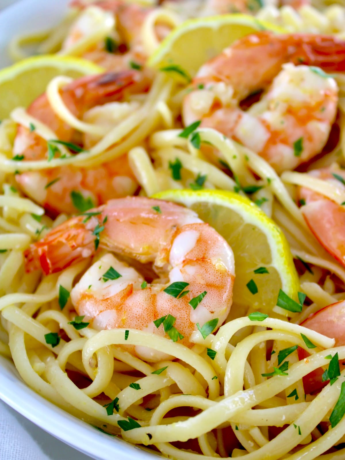 closeup of Shrimp Scampi with Linguine in white bowl with lemon slices