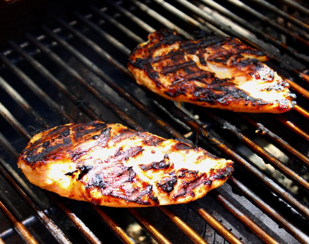 2 pieces of chicken breast cooking on grill