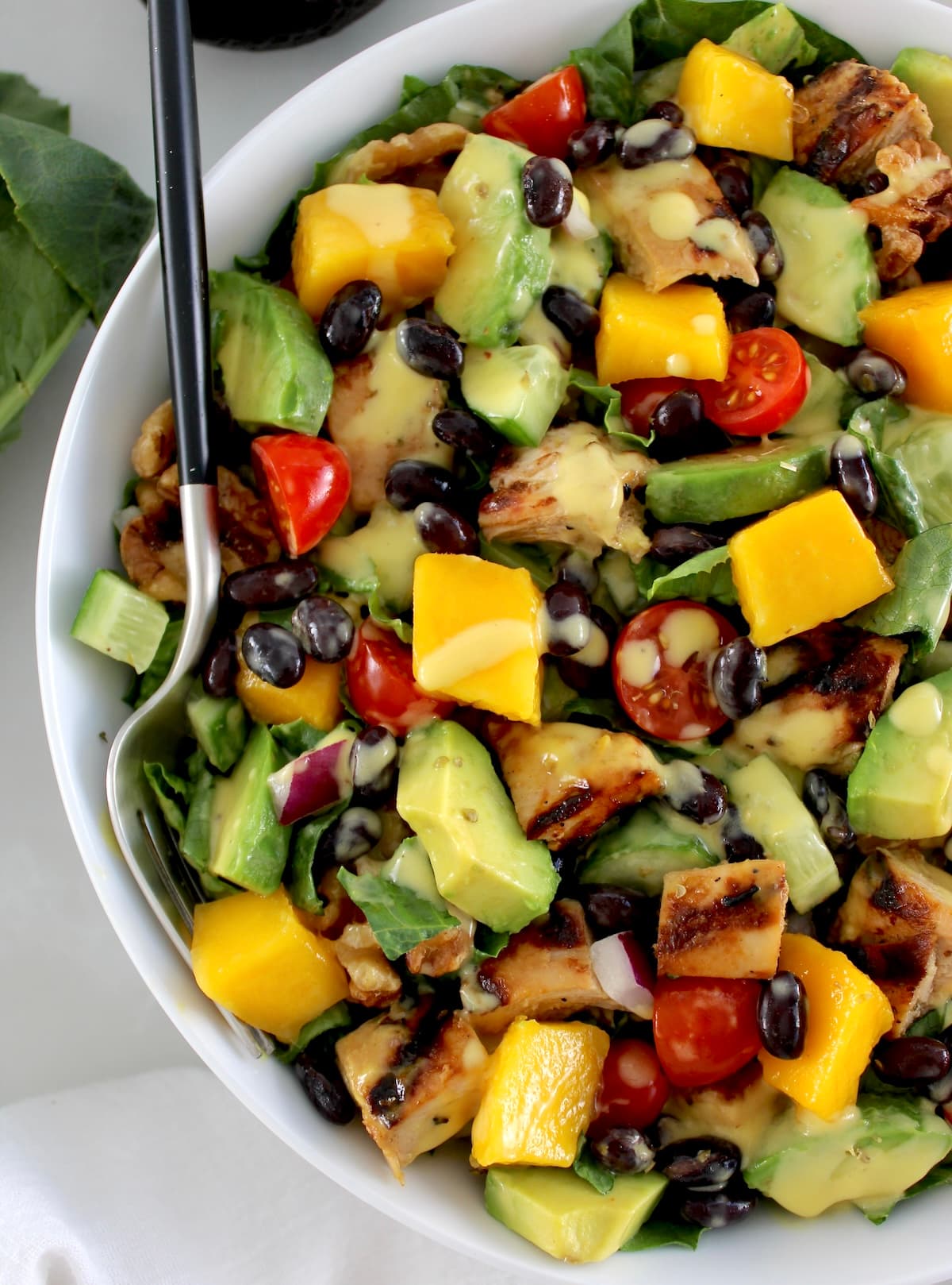 closeup of Chopped Chicken Mango Salad in white bowl with fork on side