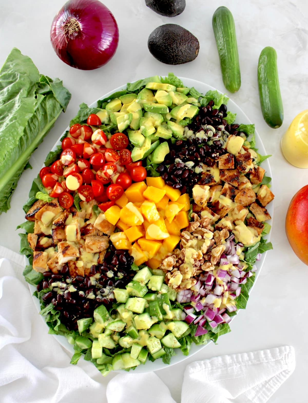 overhead view of Chopped Chicken Mango Salad on oval platter with fresh veggies in back