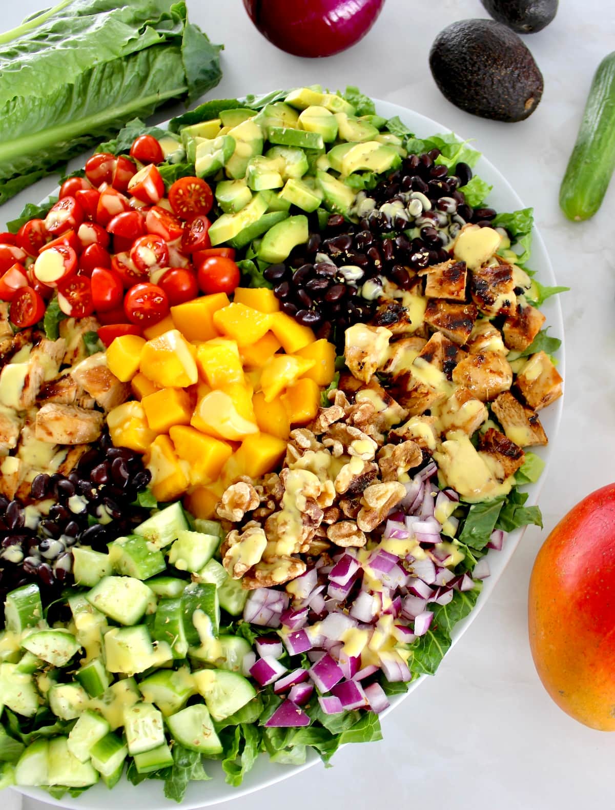 overhead view of Chopped Chicken Mango Salad on oval platter with fresh veggies in back