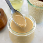 Homemade Tahini in spoon held over open glass jar