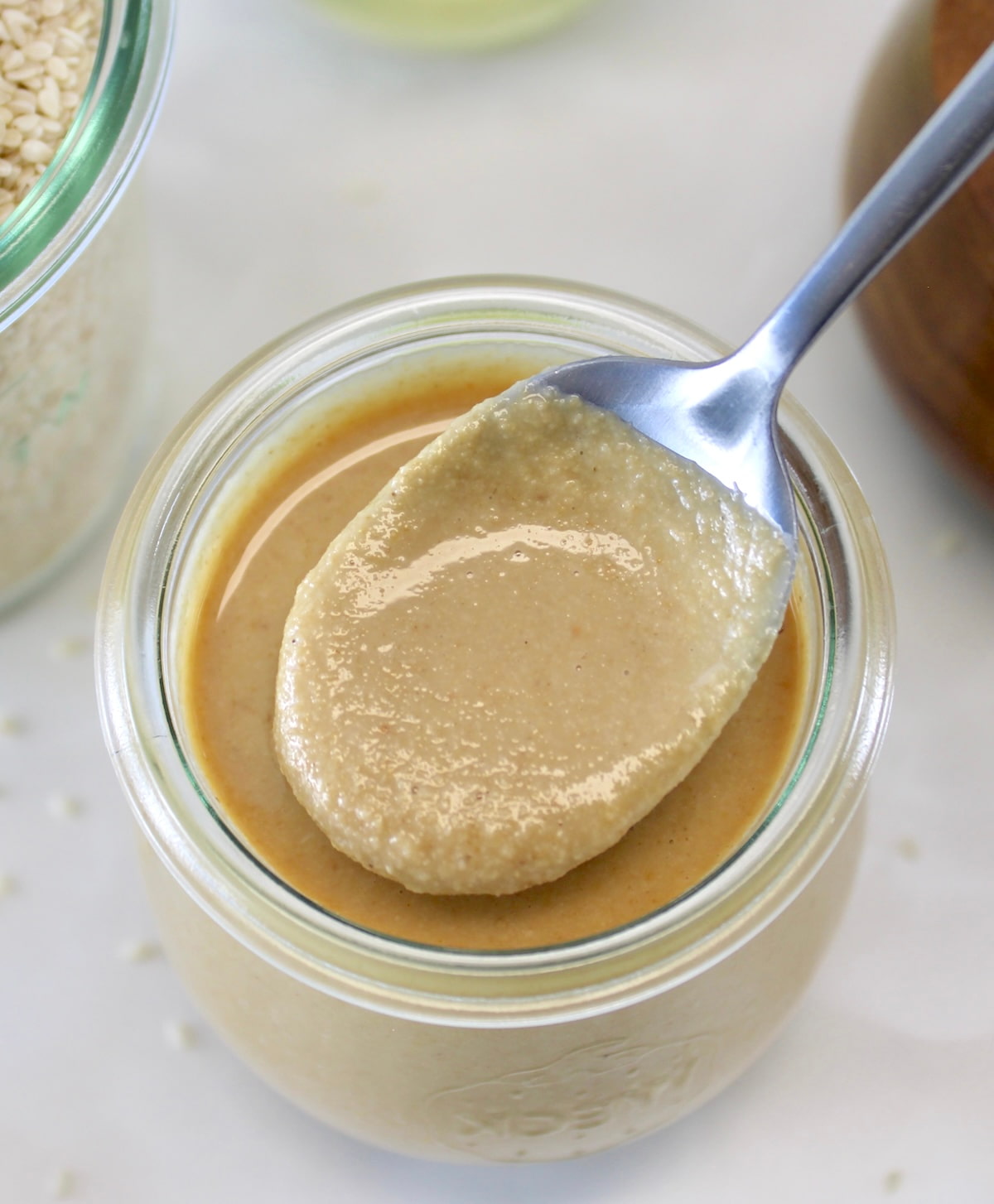 overhead view of spoonful of Homemade Tahini over glass jar