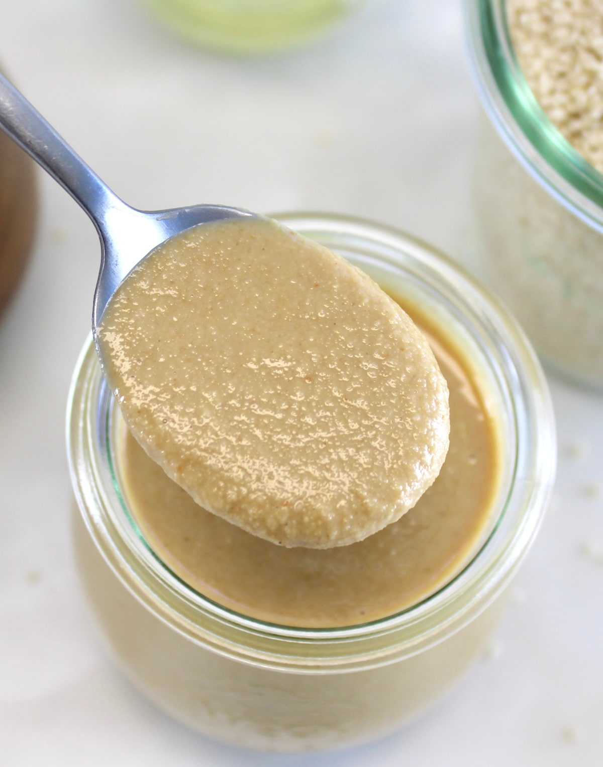 overhead view of spoonful of Homemade Tahini over glass jar