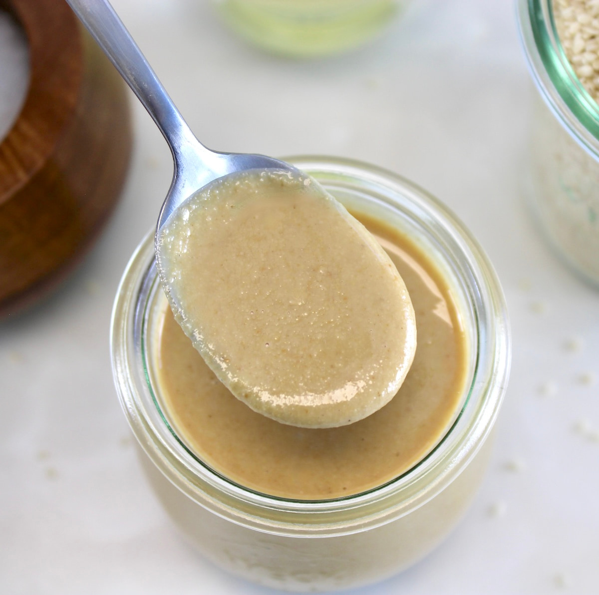 overhead view of Homemade Tahini in spoon held over glass jar