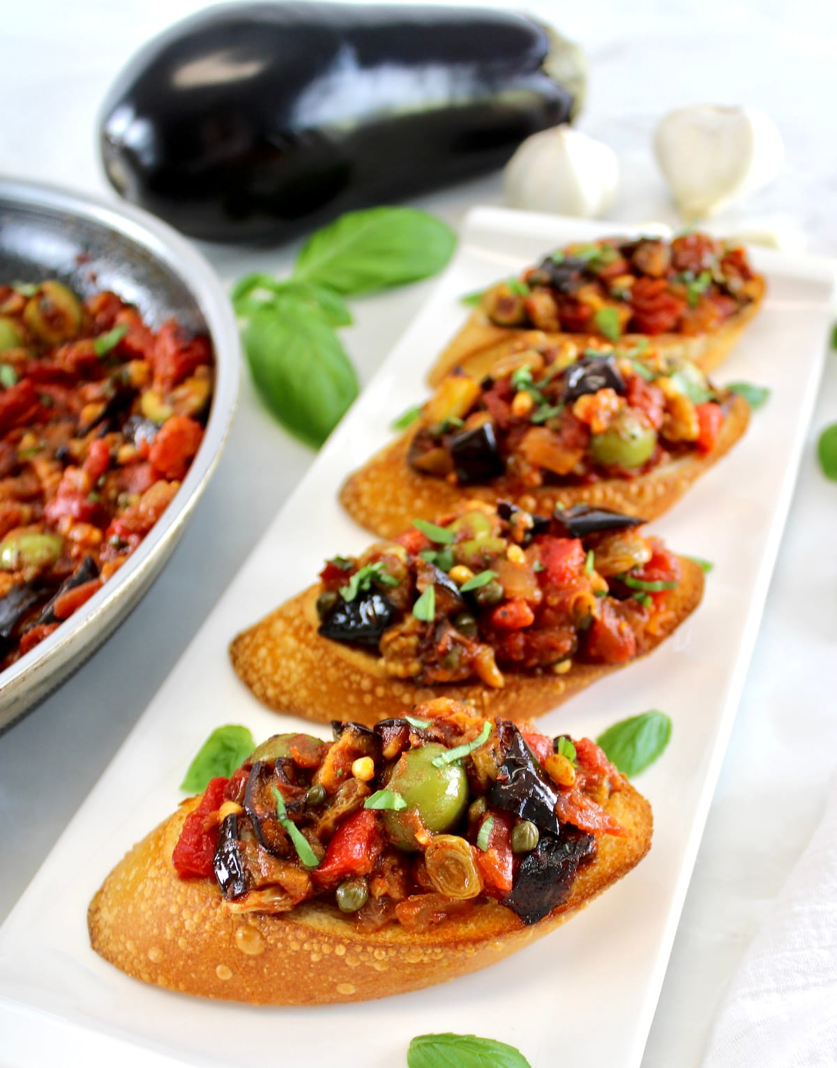 4 crostini with Eggplant Caponata on top of white platter
