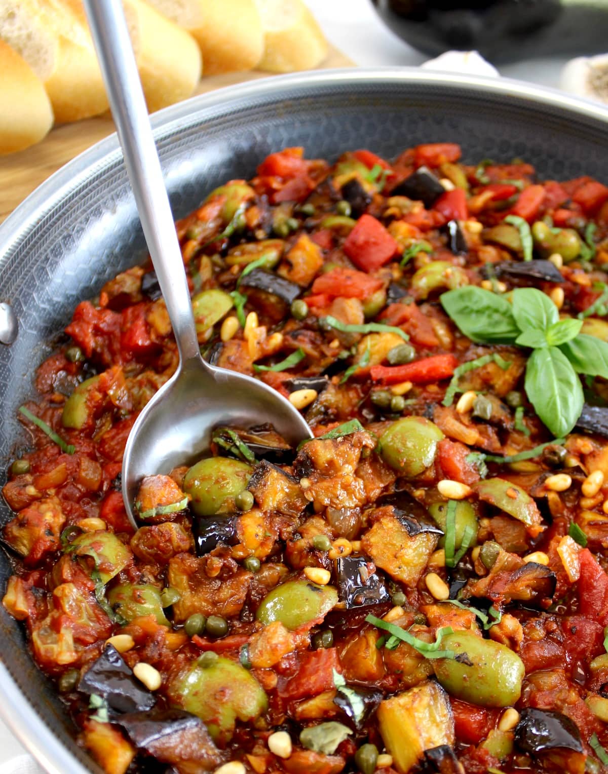 closeup of Eggplant Caponata in skillet with silver serving spoon