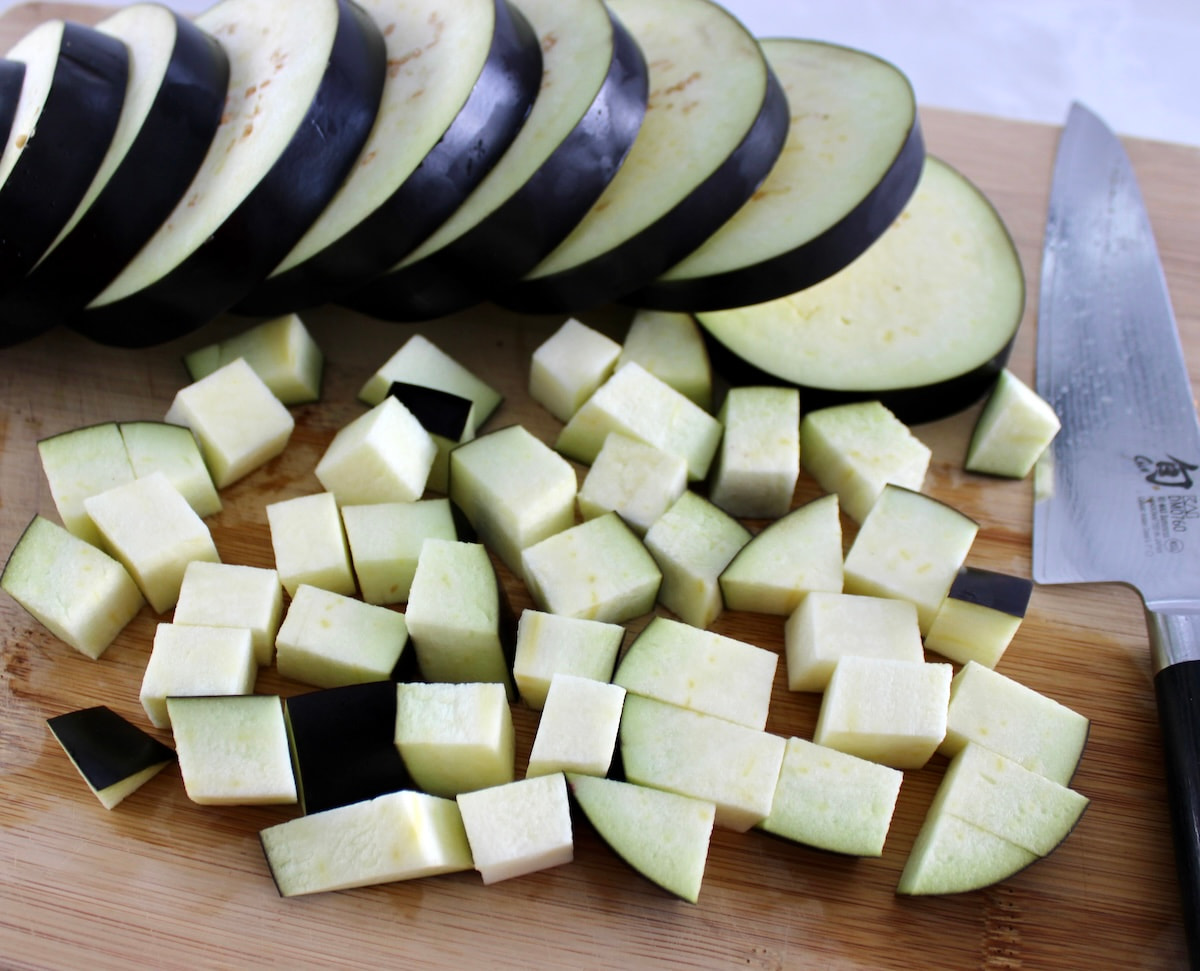 cubed eggplant on cutting board with slices in back