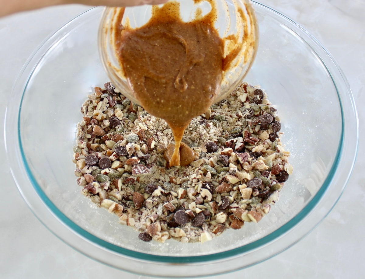 No Bake Granola Bars ingredients in glass bowl with melted honey and peanut butter pouring over top