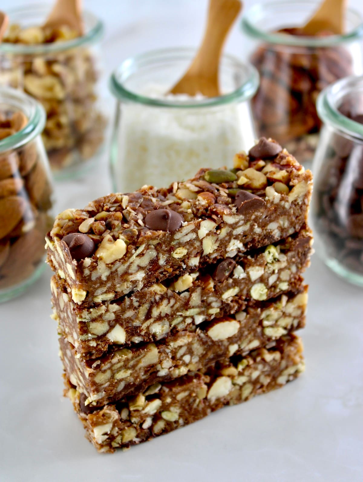 4 No Bake Granola Bars stacked up with ingredients in back