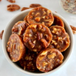 Pecan Caramel Clusters in blue bowl with pecans in back