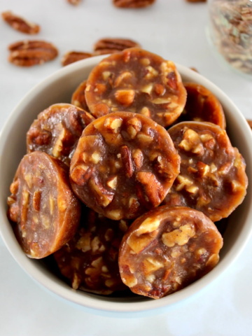 Pecan Caramel Clusters in blue bowl with pecans in back
