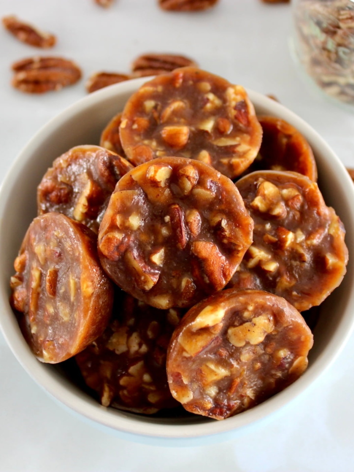 Pecan Caramel Clusters in blue bowl with pecans in back