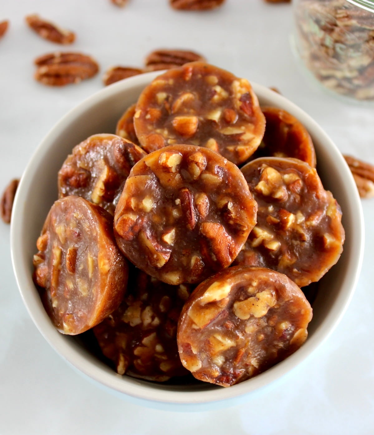 Pecan Caramel Clusters in blue bowl with pecans in back