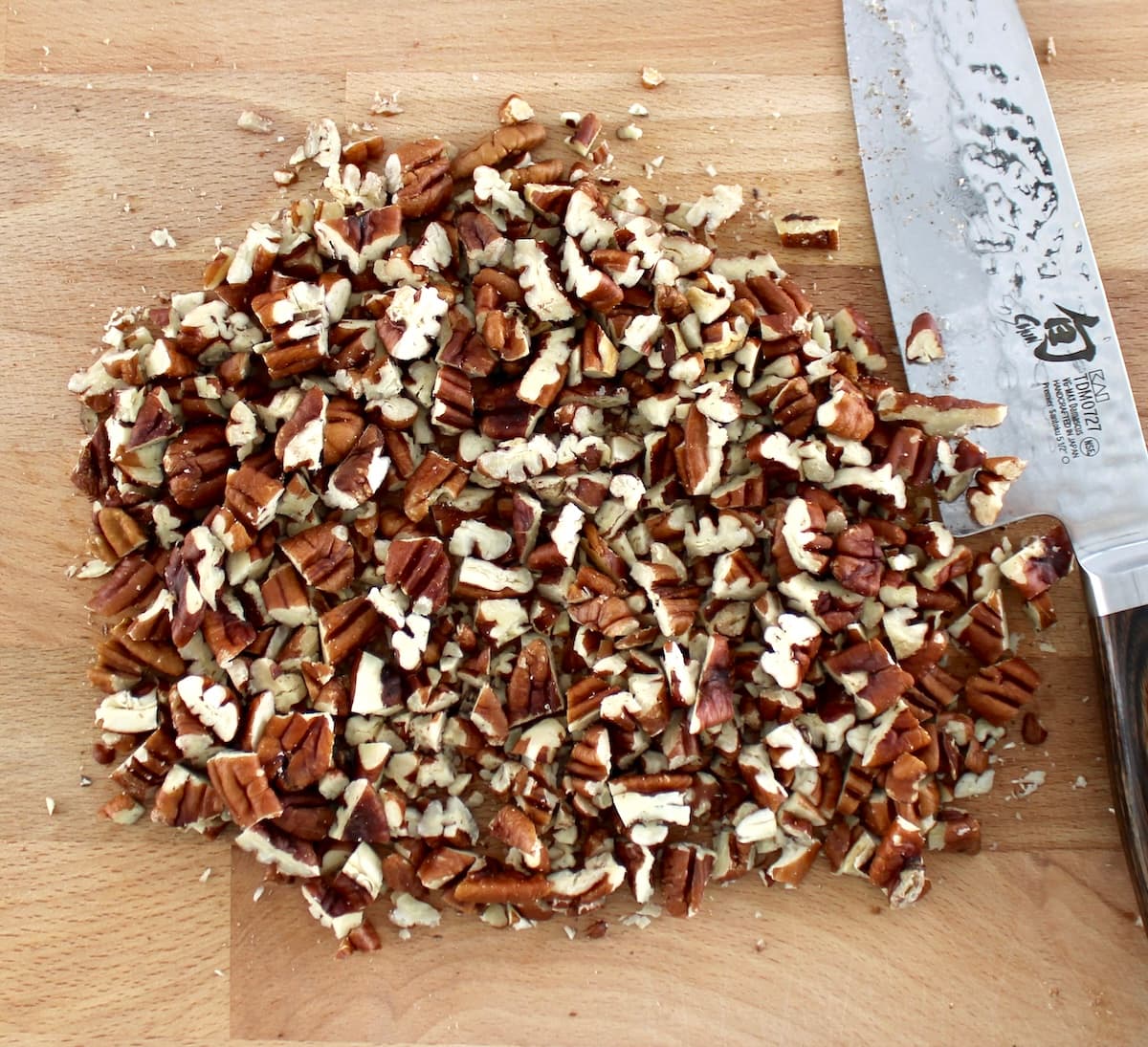 chopped pecans on cutting board with knife