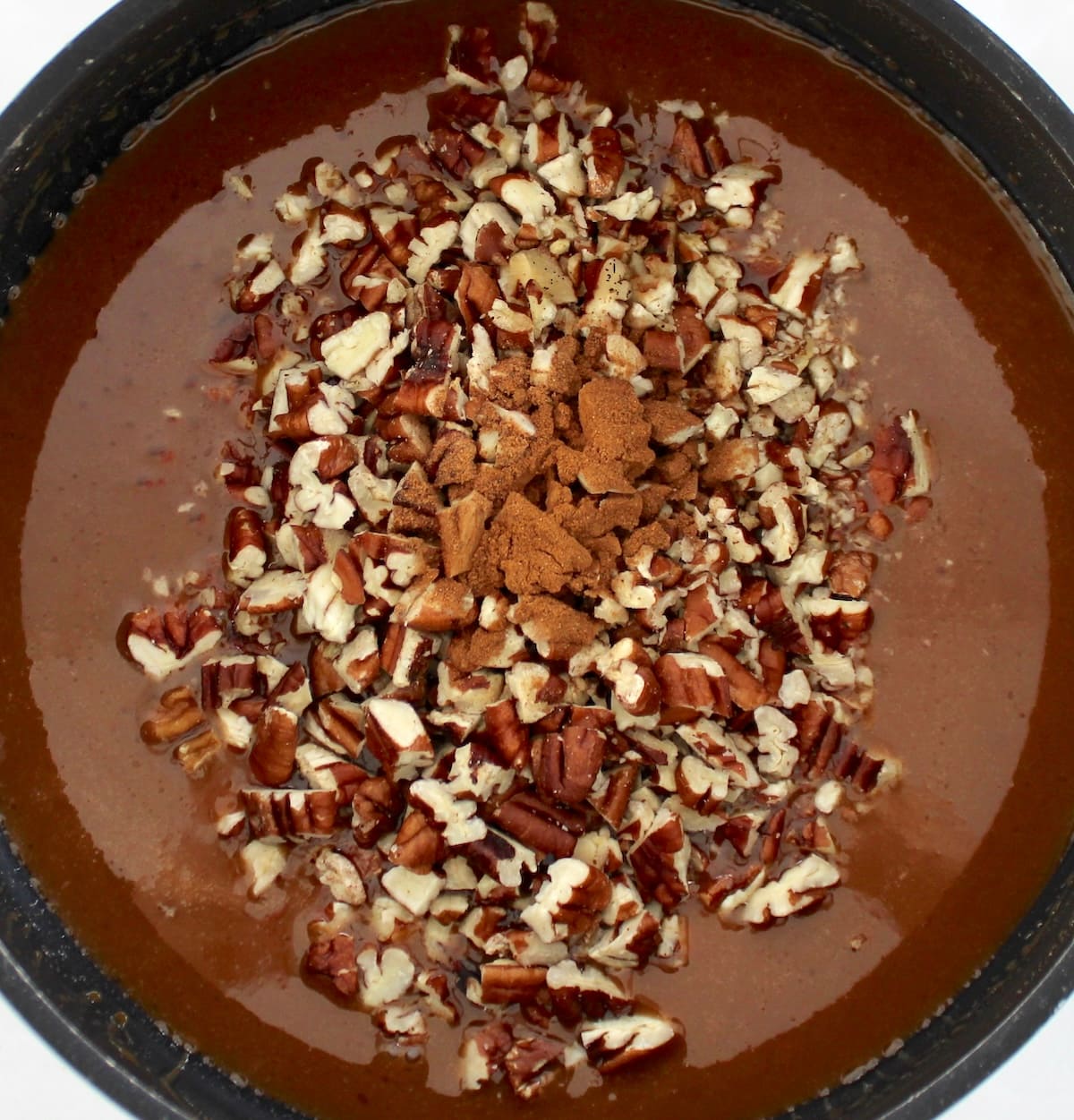 chopped pecans and cinnamon in caramel sauce in saucepan