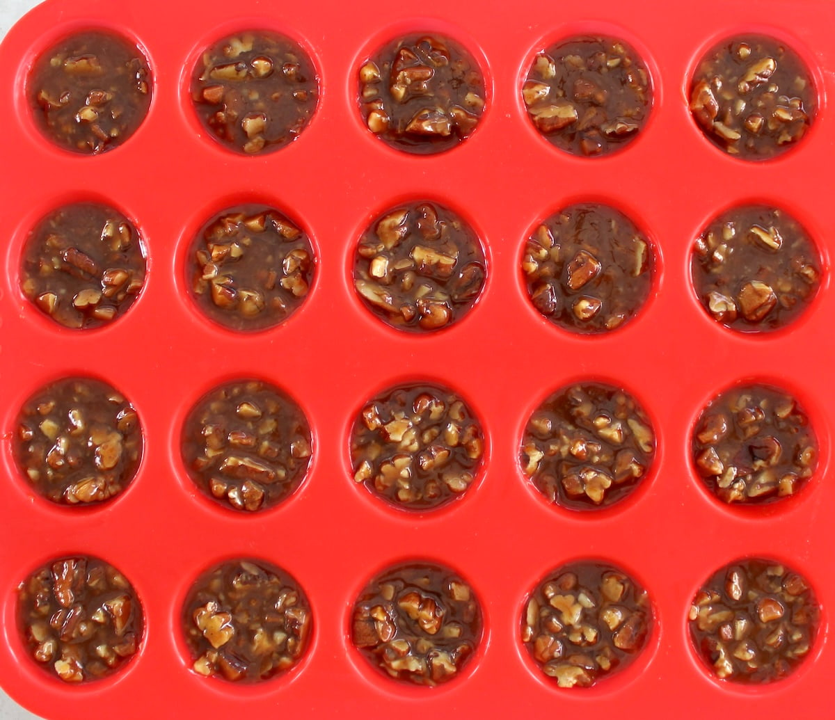 Pecan Caramel Clusters in red mini muffin silicone pan