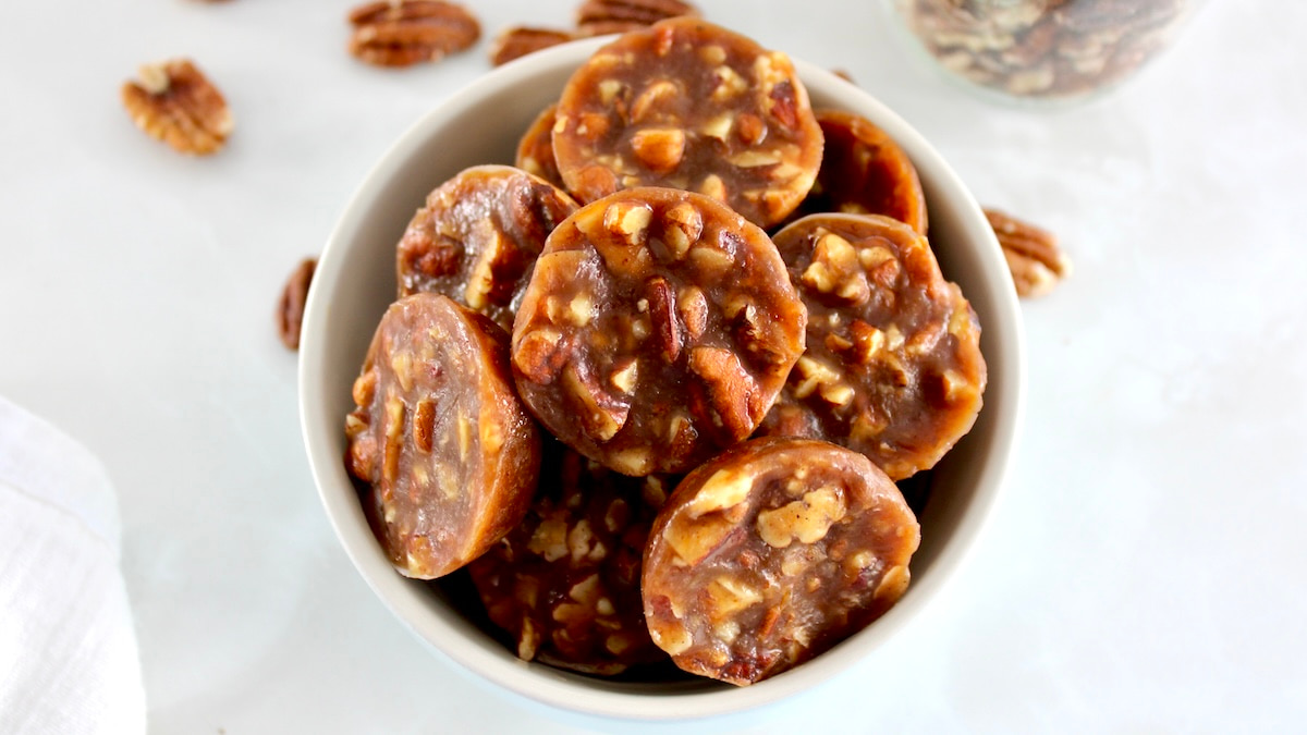 Pecan Caramel Clusters in blue bowl with pecans in back