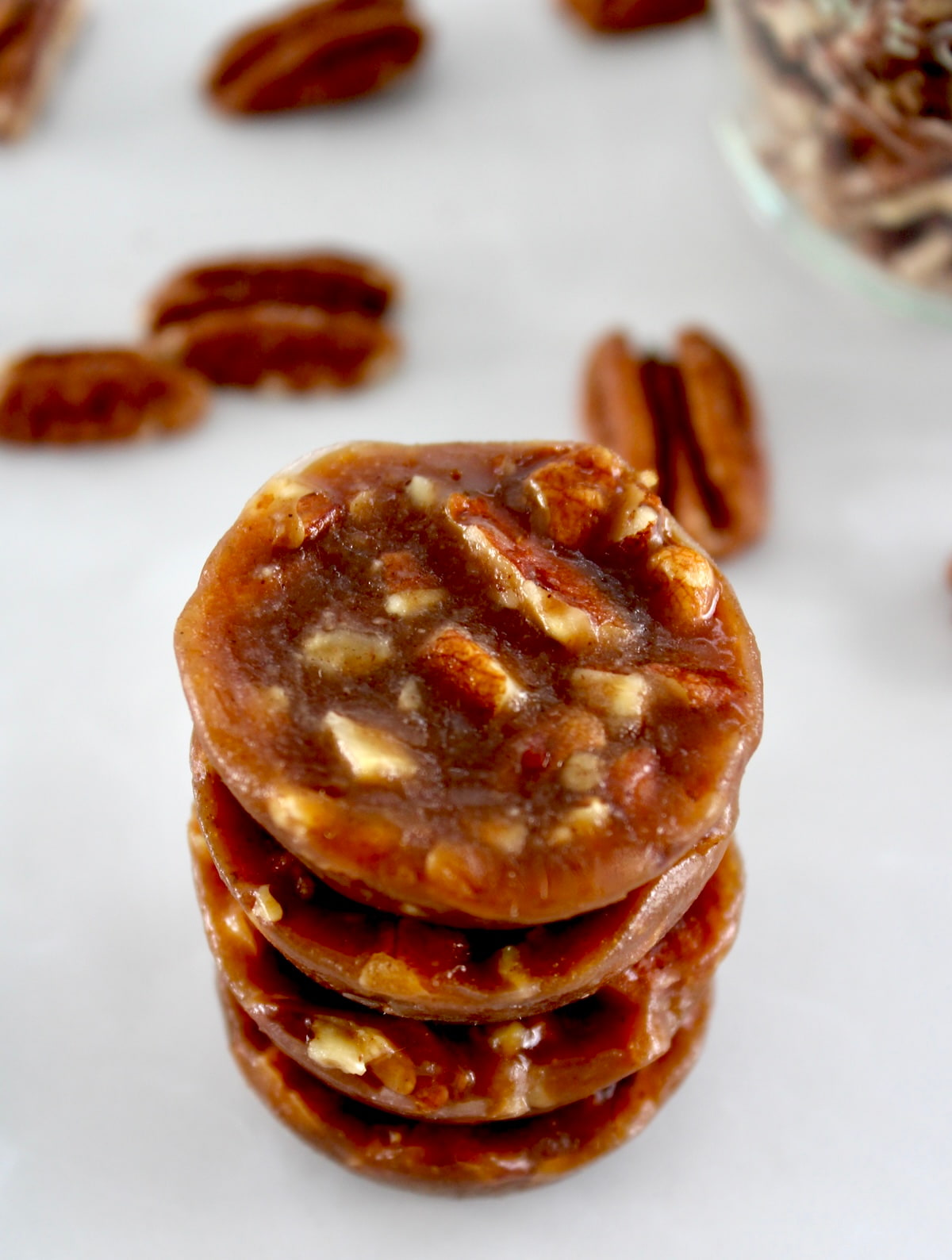 Pecan Caramel Clusters stacked up with pecans in back