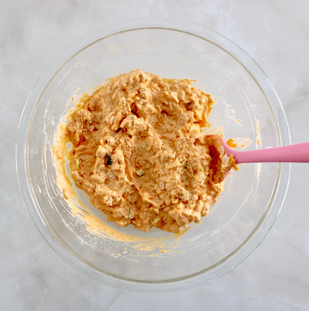 Cottage Cheese Buffalo Chicken Dip filling in glass bowl with pink spoon