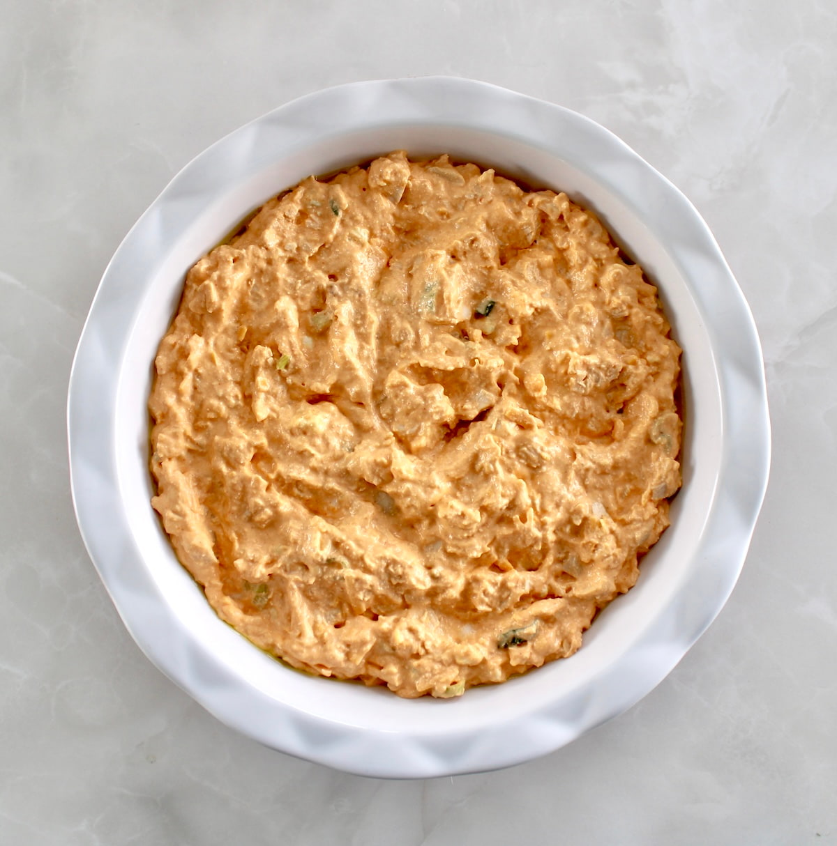 Cottage Cheese Buffalo Chicken Dip unbaked in white pie dish