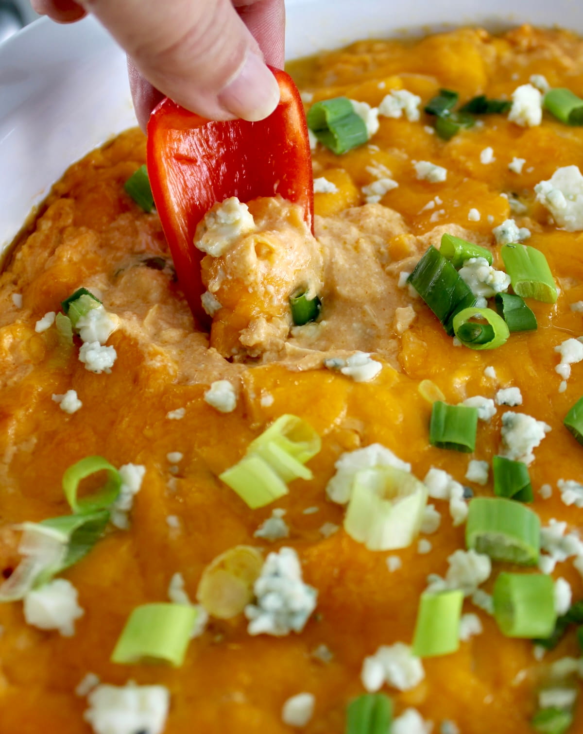 closeup of dipping red bell pepper in Cottage Cheese Buffalo Chicken Dip