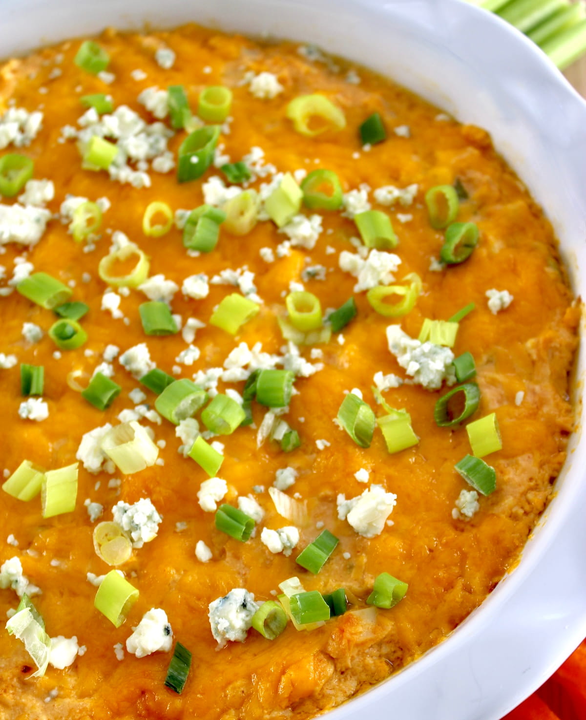 closeup of Cottage Cheese Buffalo Chicken Dip in white pie dish with scallions and blue cheese on top