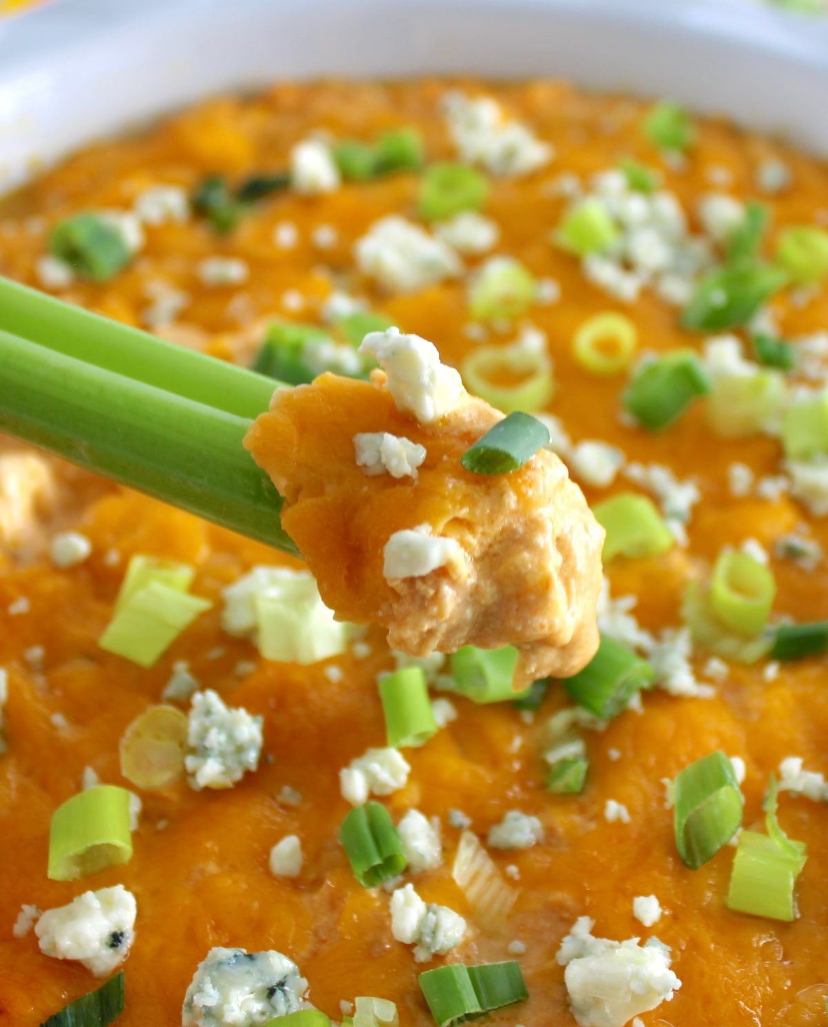 holding up celery stick dipped into Cottage Cheese Buffalo Chicken Dip