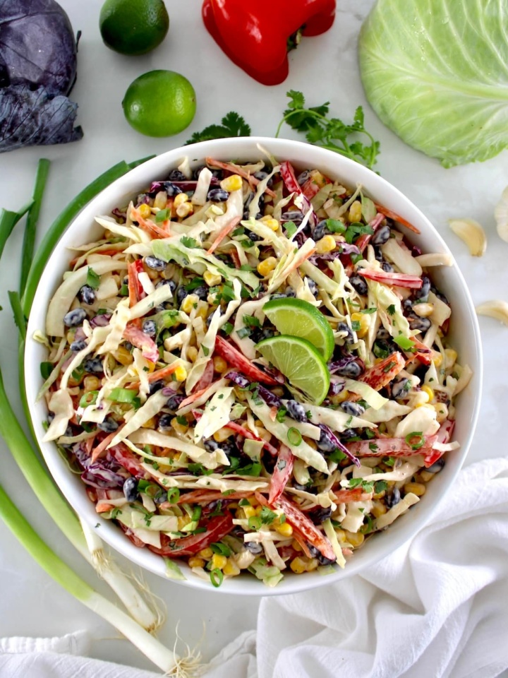overhead view of Cowboy Coleslaw in white bowl with veggies in back