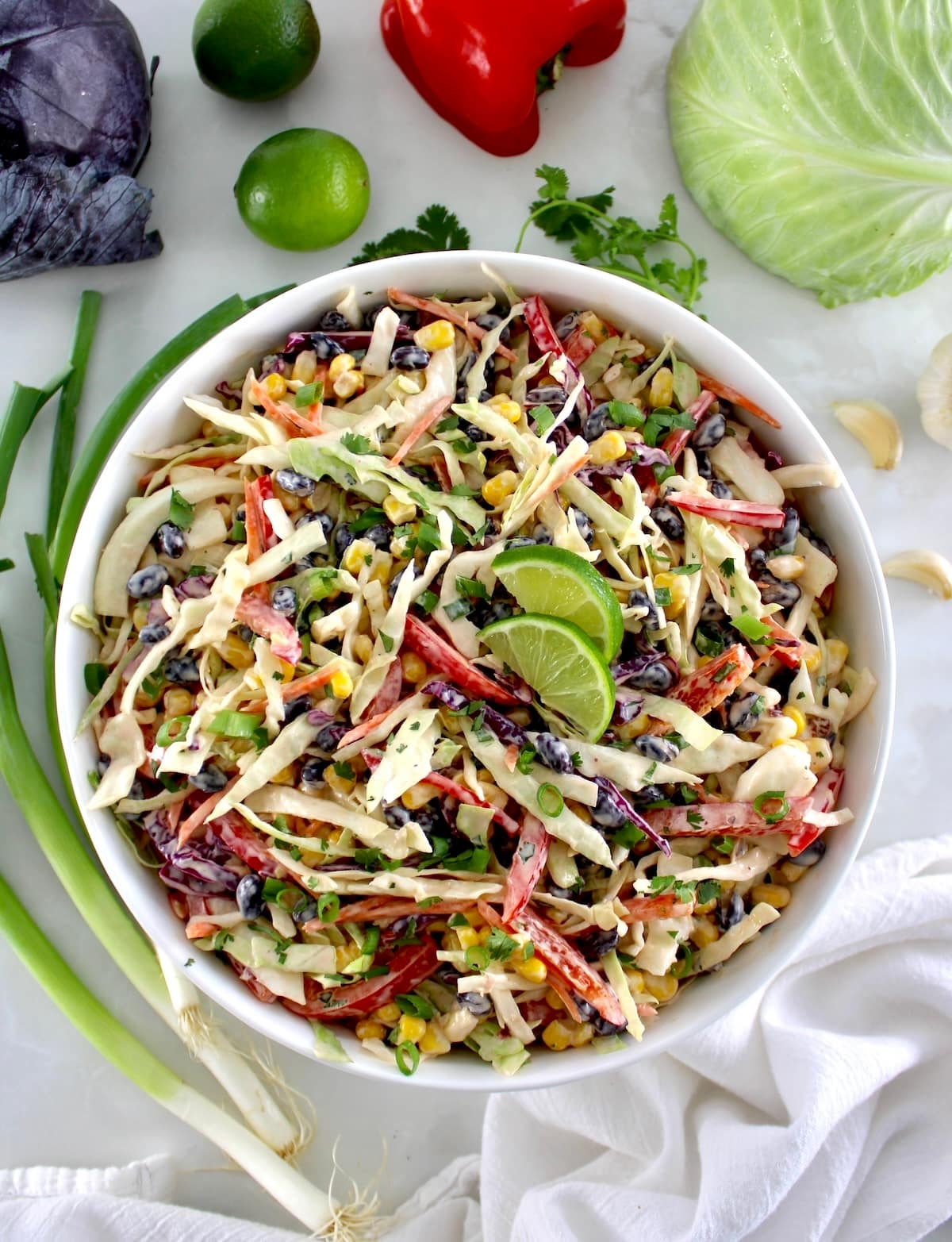 overhead view of Cowboy Coleslaw in white bowl with veggies in back