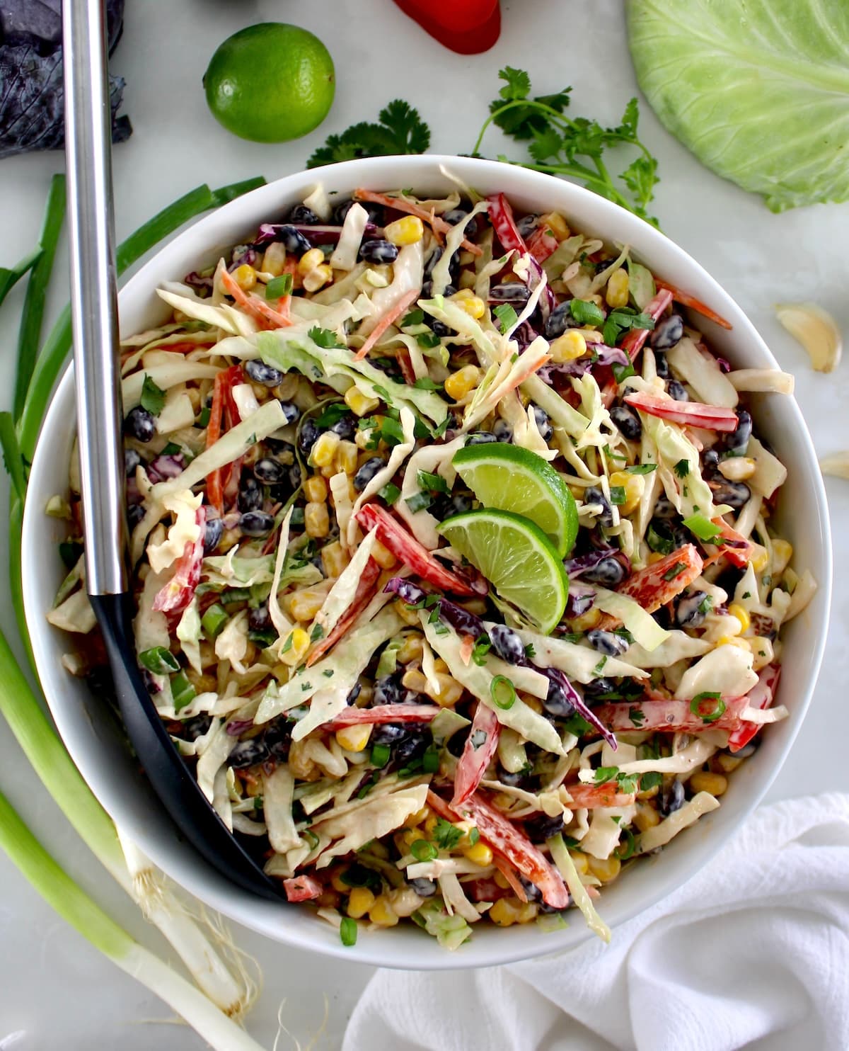 overhead view of Cowboy Coleslaw in white bowl with black serving spoon